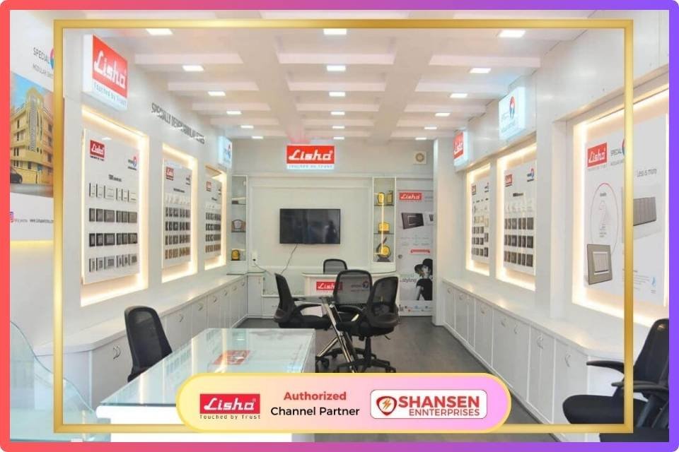 This image showcases the Lisha Switches showroom of Shansen Enterprises, an Authorized Channel Partner in Coimbatore. The showroom features a modern interior with well-lit display panels showcasing various Lisha switches, sockets, and cover plates